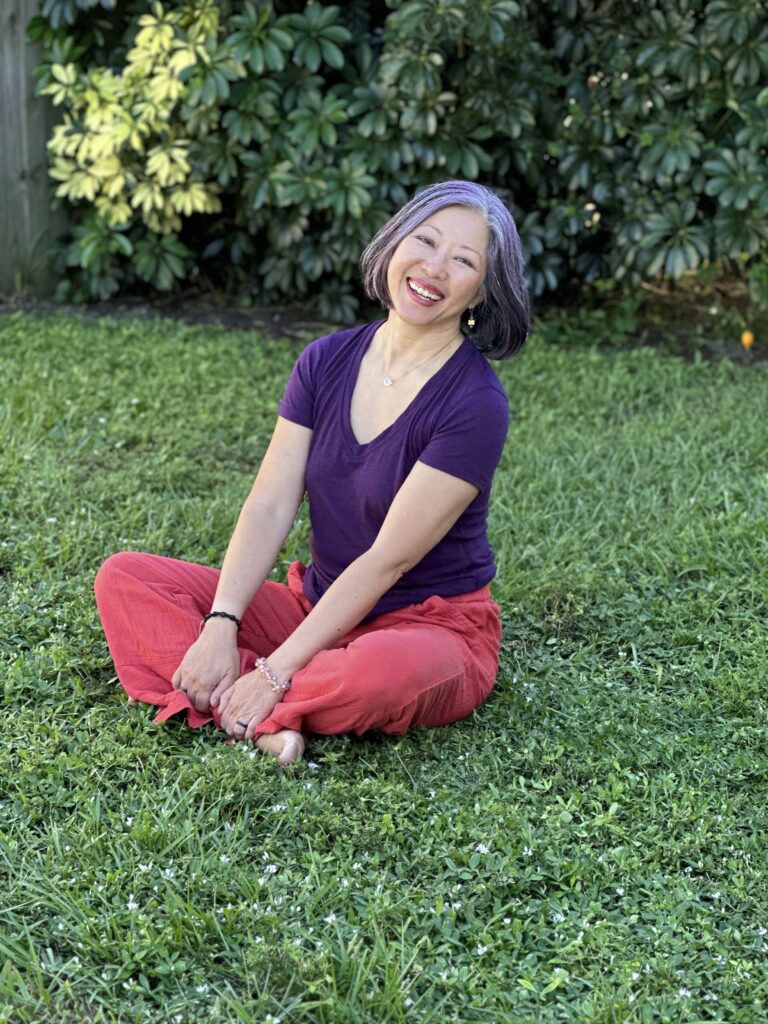 Dr. Karen sitting on the grass smiling